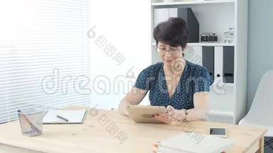 办公室里一个<strong>中年妇女</strong>用平板电脑