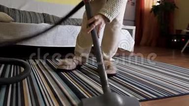 年轻女子在打扫房子里的地毯时使用吸尘器。 房屋清洁