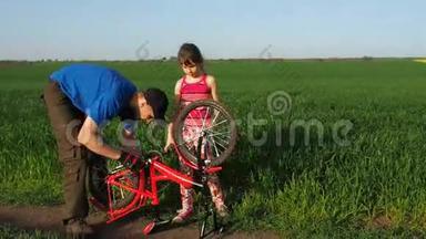一个带着孩子的人正在修理自行车。 爸爸和一个女儿在大自然中骑自行车。 那个人正在修理自行车。