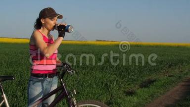 骑自行车的女孩喝水。 一个骑自行车的农村年轻女子。 一个运动女孩在喝水。