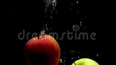 黄色和红色的苹果在黑色的背景下落入透明的水中