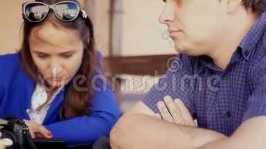 一个男人和一个女孩正坐在咖啡馆里看着摄像机屏幕上的照片高清视频镜头1920x1080