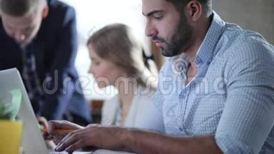 成功的多元文化商人正在笔记本电脑上打字，并在现代办公室的笔记本上做一些笔记。
