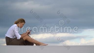 一个女孩坐在沙漠里的沙滩上打电话