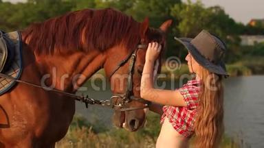 年轻女子在黄昏的夕阳下亲吻马。