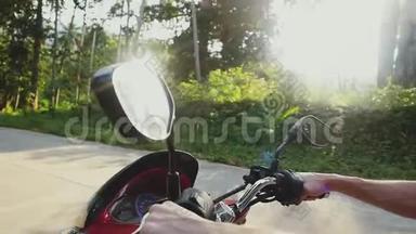 年轻的帅哥戴着太阳镜，骑着摩托车在热带阳光明媚的道路上穿过太阳，带着美丽的镜头耀斑