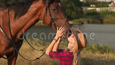 年轻女子在黄昏的夕阳下亲吻马。