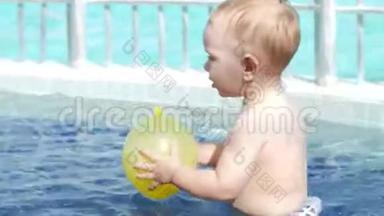 一个可爱的孩子用一个充气`黄色球在<strong>儿童游泳</strong>池里玩耍。 他用脚走在底部。