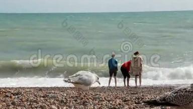英国布莱顿。 两个女孩和一个男孩在暑假站在靠近大西洋的海滩上。 那个家伙