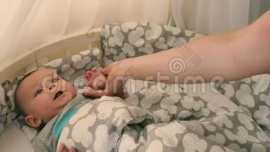 母亲牵着一个婴儿的手把婴儿床放在婴儿床上