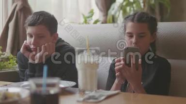两个可爱的孩子一起室内一起喝奶昔或调味饮料，慢动作<strong>视频</strong>使智能手机处于运行<strong>状态</strong>