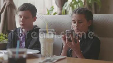 两个可爱的孩子一起室内一起喝奶昔或调味饮料，慢动作<strong>视频</strong>使智能手机处于运行<strong>状态</strong>