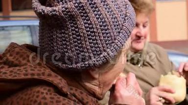 两位年长的妇女赤手空拳地在街上吃猪肉香肠，在塞尔维亚<strong>伏</strong>伊<strong>伏</strong>丁那的贝洛布拉托举行的宰猪节，