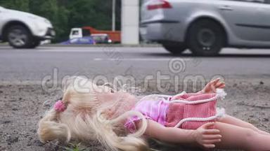 娃娃躺在马路附近，<strong>车水马龙</strong>. 许多汽车从后面来。