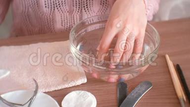 家里的手法。 女人把手伸进一碗水里。 手特写，美甲工具<strong>放在桌面</strong>上..