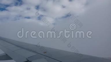 从飞机窗口到飞机机翼的视图。 飞机在云上飞行。