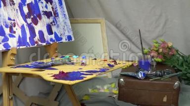 画家`工作场所，一个木制调色板在油画，画布，<strong>油漆</strong>和<strong>刷子</strong>。 到处都是鲜花
