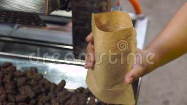 亚洲女人把煎好的可可豆放在釉里的纸袋里