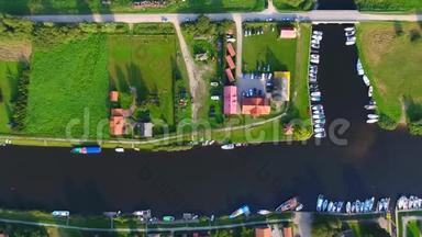 靠近河边的村庄。 阳光明媚的夏日，无人机摄像机垂直倾斜在河边的小村庄上。