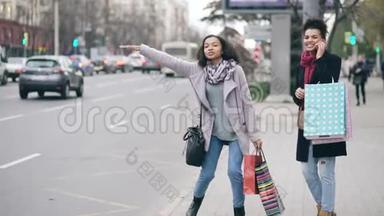 两个有魅力的非洲裔美国妇女，带着购物袋，从<strong>商场</strong>销售回来时叫出租车