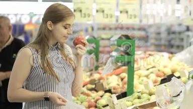 有魅力的年轻女人在超市里选择水果-新鲜苹果。 购物和人的概念。 股票视频