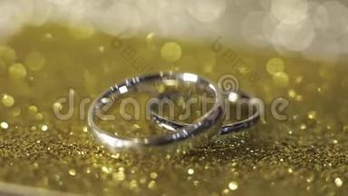 婚礼银环躺在闪亮的光泽表面。 光芒四射。 特写
