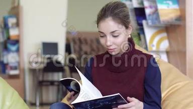 微笑浪漫女学生在阅览室翻阅一本书的画像