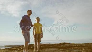 年轻的父亲和他可爱的儿子正在欣赏海洋的奇妙景色