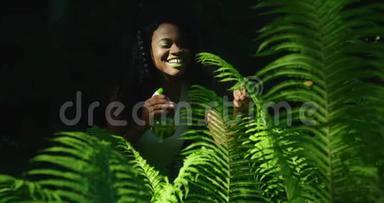 活泼开朗的美国黑人妇女的绿色成分，涂着绿色的口红和眼影，用蕨类植物喷洒