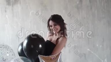 一个穿着黑色裙子的漂亮女孩手中的气球。 年轻的女人在跳舞，玩得开心，笑得开心