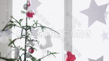 纸星星挂在窗户旁边的一棵圣诞树的前景上。 慢动作。 3840x2160