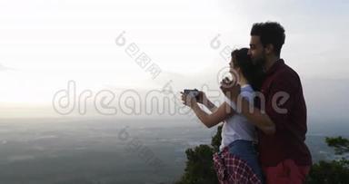 山顶上的一对情侣用<strong>手机</strong>拍照，<strong>日</strong>出时男女拥抱