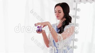 在紫罗兰色的罐子里测试每日香喷喷的面霜，微笑的女孩拿着一罐<strong>护肤品</strong>