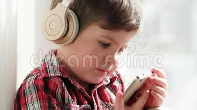 戴着耳机听音乐的孩子，穿着格子衬衫的男孩在智能手机上看动画片