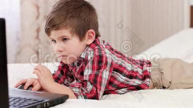 小男孩使用笔记本<strong>电脑</strong>，聪明的<strong>孩子</strong>躺在床上<strong>玩电脑</strong>网络游戏，电子设备