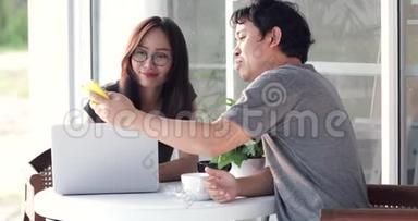 快乐的亚洲男人和女友一起使用手机和笔记本电脑