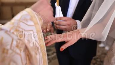 牧师双手把结婚戒指戴在新婚夫妇手上的特写镜头。 结婚典礼。