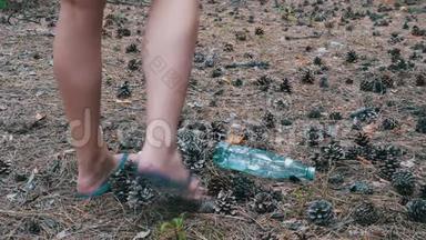松林中的塑料瓶。 女人用脚踩着塑料瓶