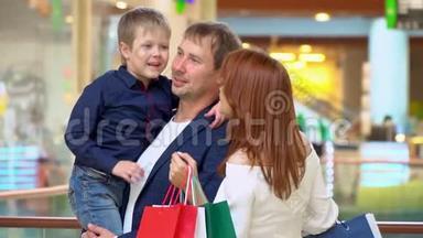父母在贸易商场和儿子说话。 这家人在购物中心为圣诞节买东西。 圣诞节