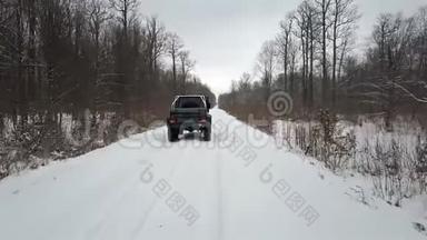 从空中观看越野车6x6，在冬天的森林里骑在白雪<strong>覆盖</strong>的<strong>道路</strong>上，后景
