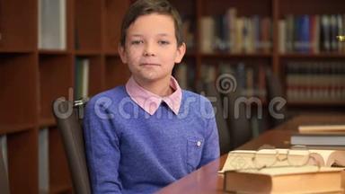 这位可爱的小学生坐在图书馆书架旁的画像