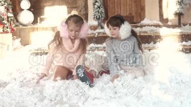 圣诞节或新年。 穿着毛皮耳机的孩子坐在人造雪上。 两个小女孩的肖像。 姐<strong>妹</strong>姐<strong>妹</strong>姐<strong>妹</strong>