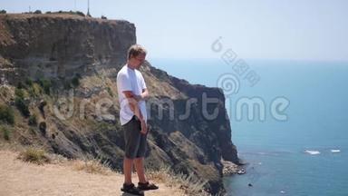 一个人站在悬崖的边缘，休息和欣赏华丽的景色。 高清，1920x1080。 慢动作。