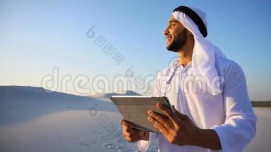 夏天，在<strong>大沙漠</strong>中站着的一幅欢快的阿拉伯游客画像，他在小工具上打印笔记。