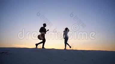 两个相爱的心，男人和女孩正在享受乐趣，并在<strong>夏天</strong>的<strong>夜晚</strong>在沙漠的山丘上奔跑，开放