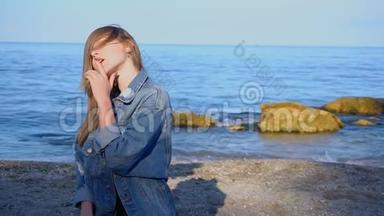 可爱的女孩去了黑海海岸，微笑着看着远方，在凉爽的夏日站在海滩上。