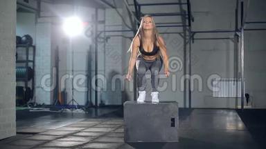 年轻强壮的金发女人，穿着<strong>运动服</strong>，在健身房做一套盒子跳跃。 <strong>女孩</strong>跳进去