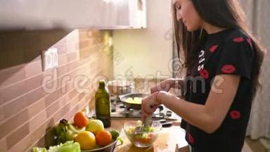 快乐的黑发女人穿着家居服在厨房做饭。 她做了一些新鲜的沙拉
