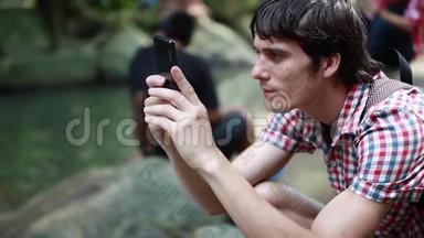 男人坐在公园旁边的池塘用智能手表检查手机。 1920x1080
