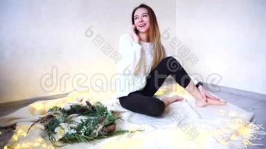 年轻的美女在<strong>平安</strong>夜打电话，坐在格子花格里，有花环和圣诞树